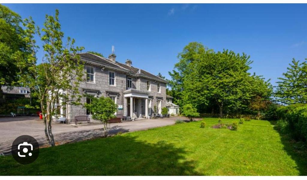a large white house with a lawn in front of it at Woodside House in Aberdeen
