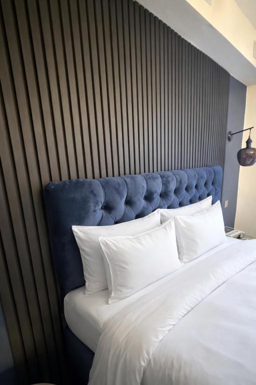 a large bed with a blue headboard and white pillows at City Rooms by Hiive in Worcester
