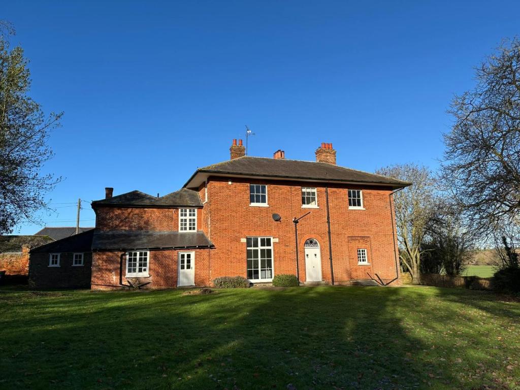 a large brick house on a grass field at Finest Retreats - Clavering Hall in Saffron Walden