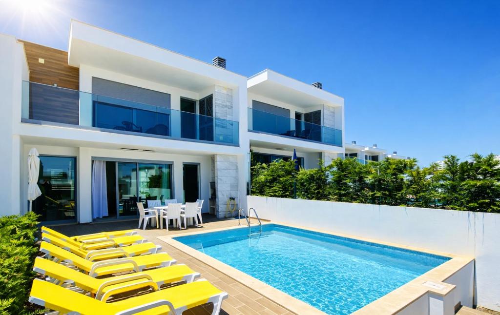 a villa with a swimming pool and yellow chairs at Albuhera - Private Pool - 8 Guests - Albufeira in Albufeira