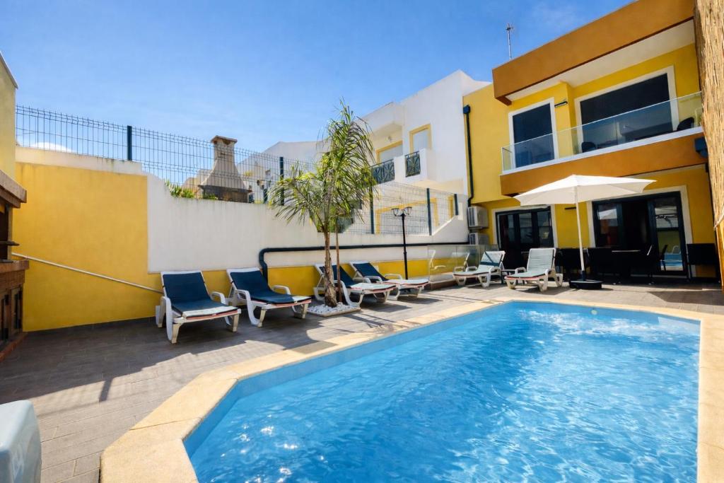 a swimming pool with chairs and a house at Alice - Private Pool - 10 Guests - Albufeira in Albufeira