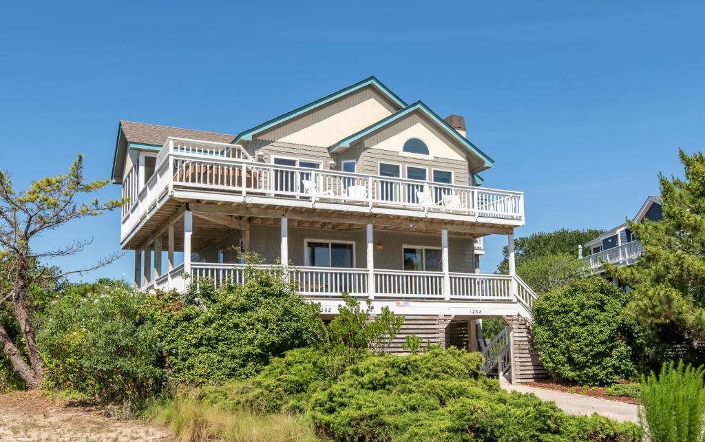 a large house with a wrap around deck at Into the Sun - Corolla, Villages at Ocean Hill, 75 Yds to Beach, Hot Tub, Community Pool, Pets OK, Flex Stays in Corolla