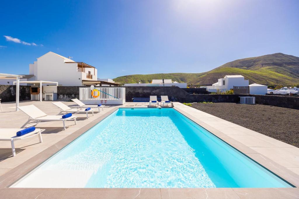 a swimming pool with lounge chairs and a house at Villa Yaiza Secret 3 in Yaiza