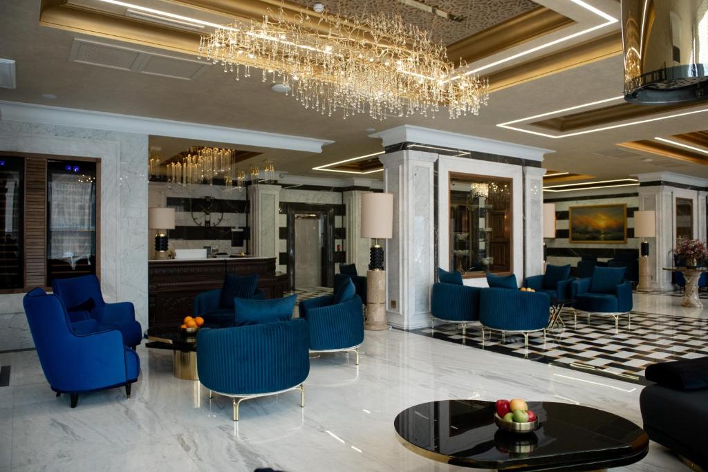 eine Lobby mit blauen Stühlen und einem Kronleuchter in der Unterkunft Aivazovsky Congress Hotel & Spa in Gjumri