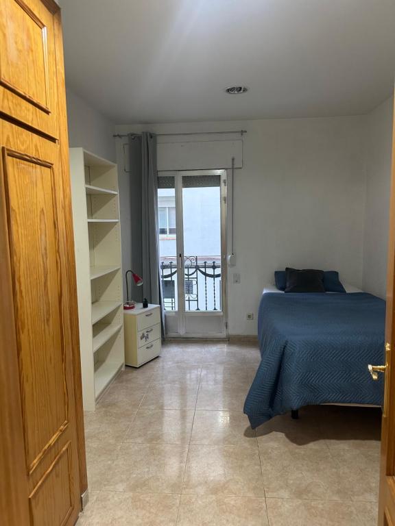 a bedroom with a bed and a door to a balcony at Habitación individual in Madrid