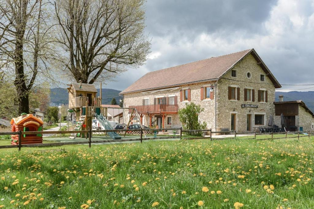 a house with a playground in front of a field at Gîte Le Chalimont in Saint-Julien-en-Vercors