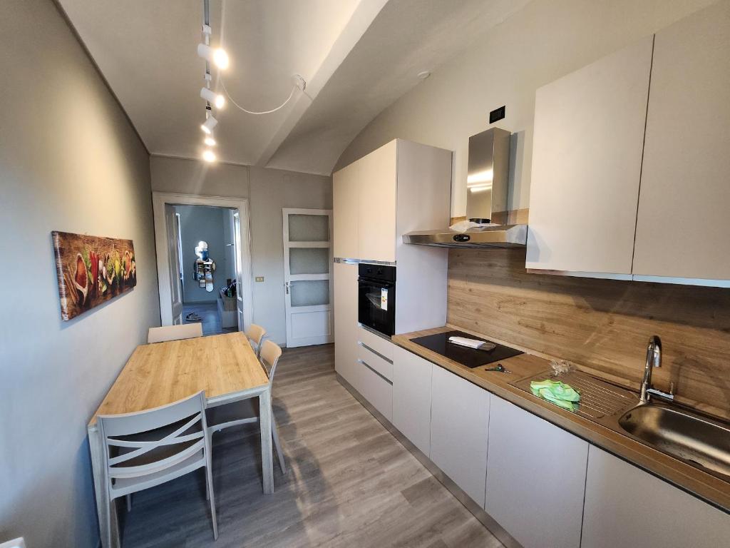 a kitchen with white cabinets and a wooden table at Casa di ringhiera 1 in Pinerolo