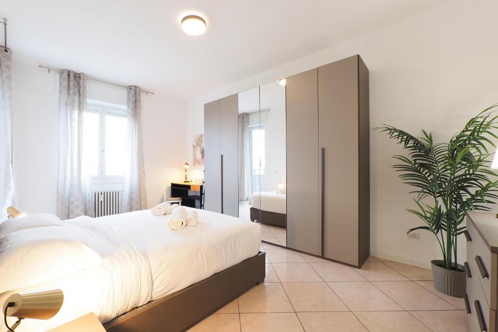 a bedroom with a large white bed and a plant at Primopiano - Olgettina in Vimodrone