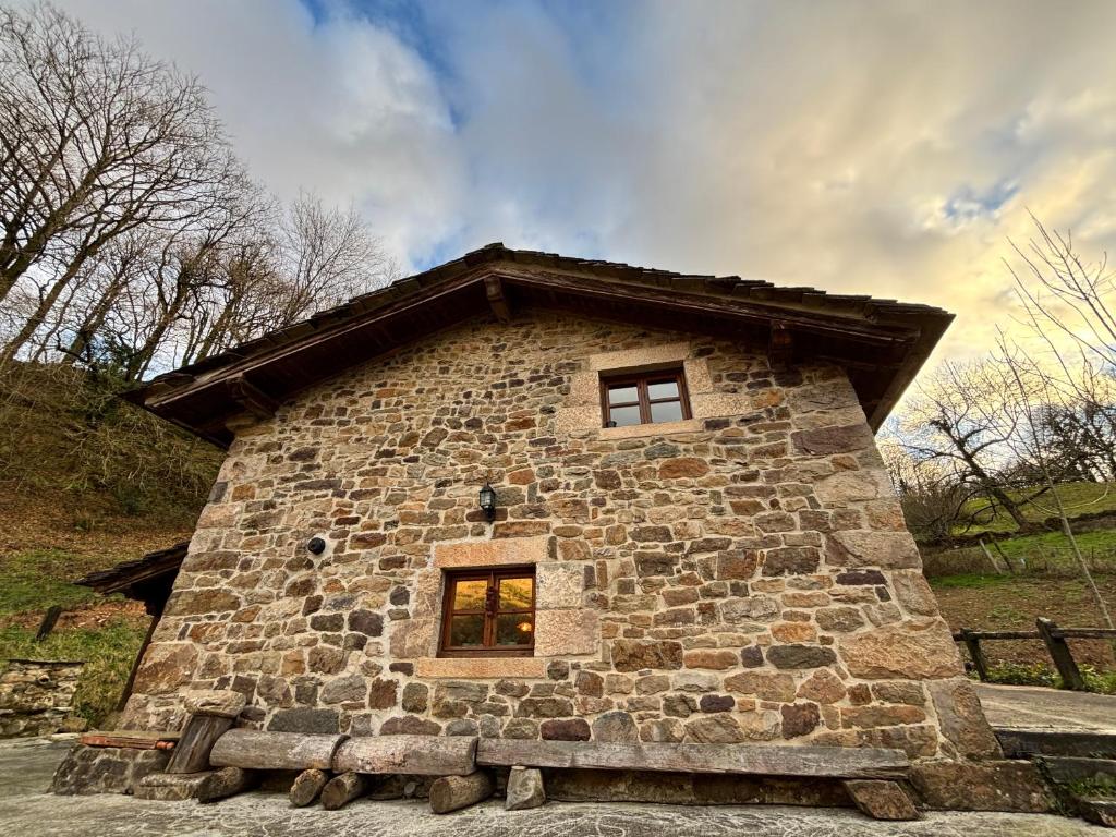 a stone building with a window on top of it at Cabaña Los Picones in Pisueña