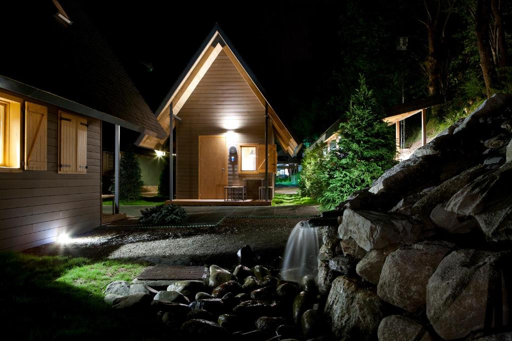 a waterfall in front of a house at night at Bungalows Verneda Mountain Resort in Arrós