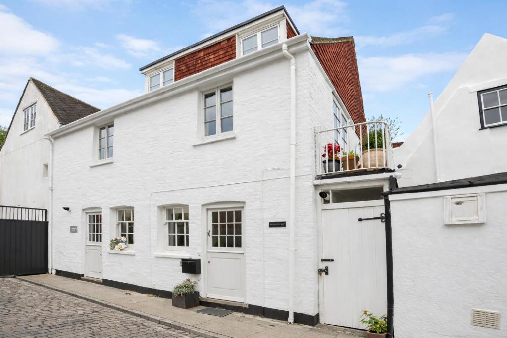 a white house with a balcony on a street at LB Newgate in Lymington