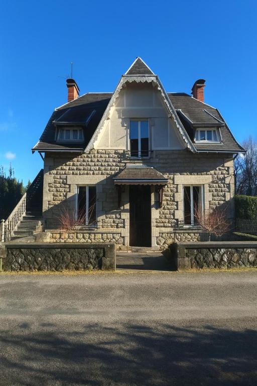 a stone house with a front door and stairs at La Cigalienne in Treignac
