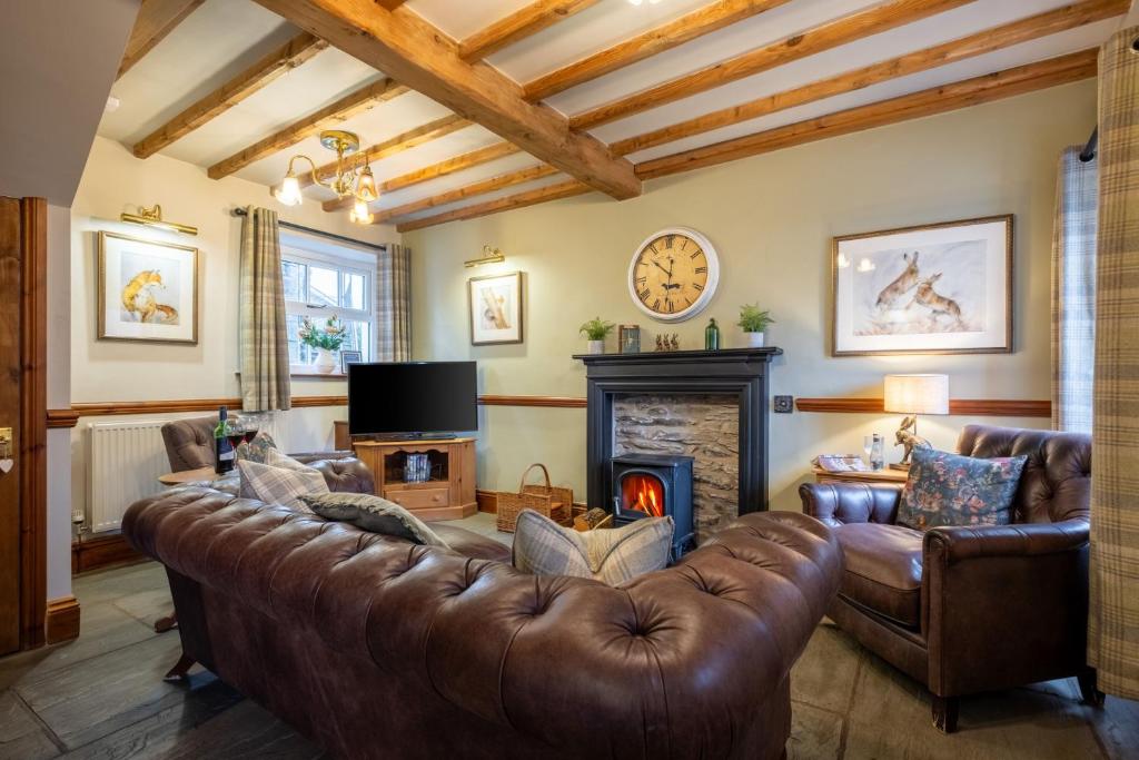 a living room with a leather couch and a fireplace at Smithy Cottage in Hawkshead