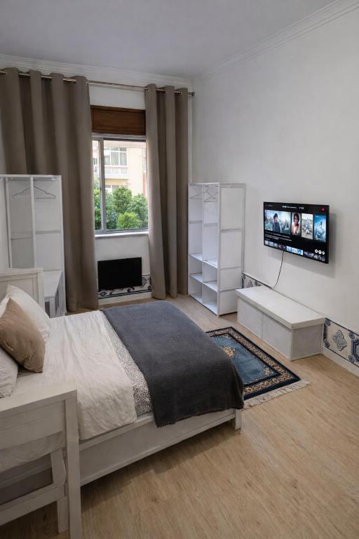 a bedroom with a bed and a flat screen tv at Quarto individual perto de Lisboa e Sintra in Queluz