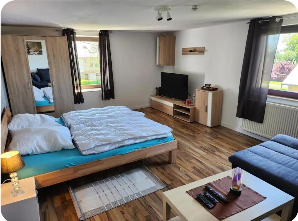 a bedroom with a bed and a couch and a tv at Gästewohnung Rauw in Saint-Vith