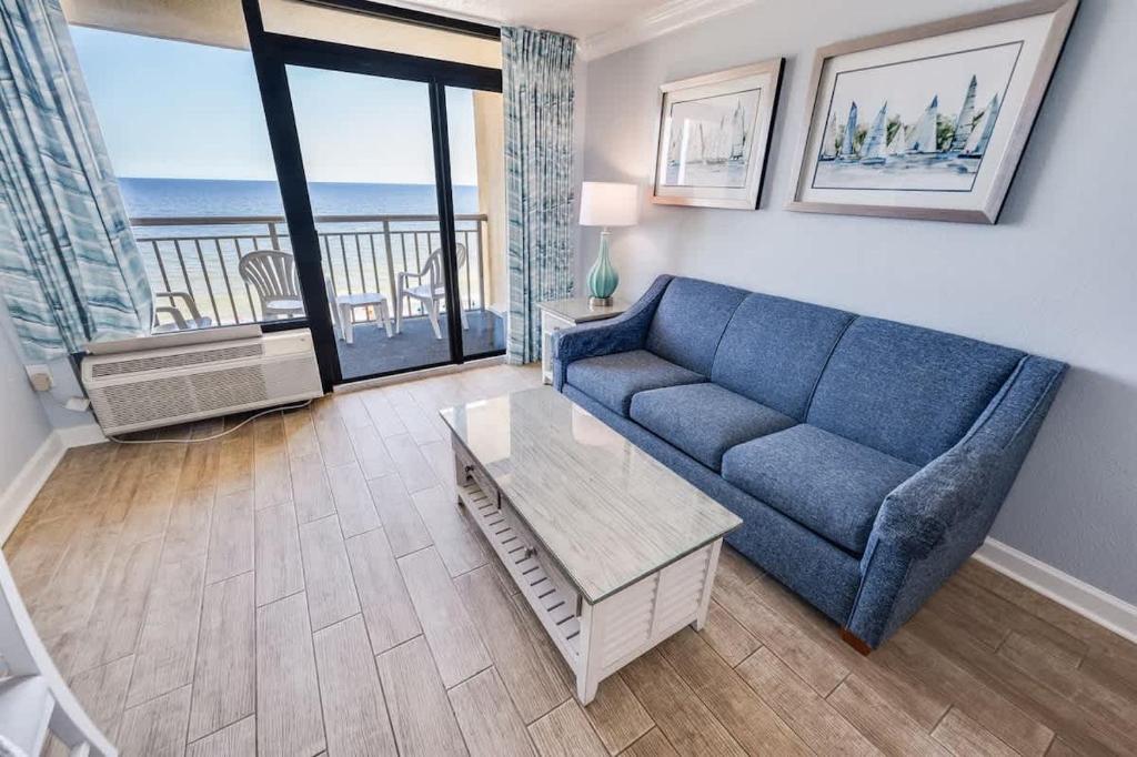 a living room with a blue couch and a balcony at Prime Ocean Frontage The Pavilion in Myrtle Beach