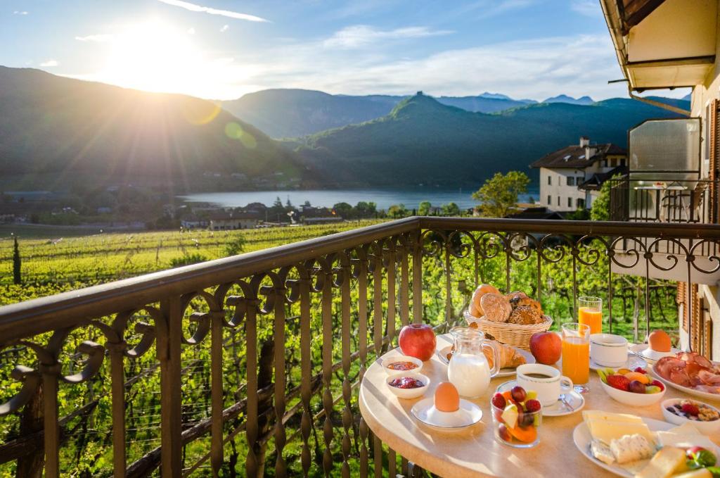 a table with breakfast food on a balcony with a view at Vogelmaierhof am Kalterer See in Caldaro