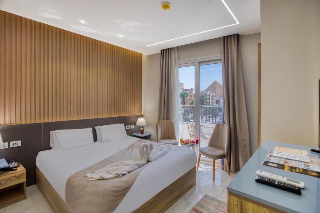 a bedroom with a bed and a desk and a window at Horizon Pyramids Boutique in Cairo