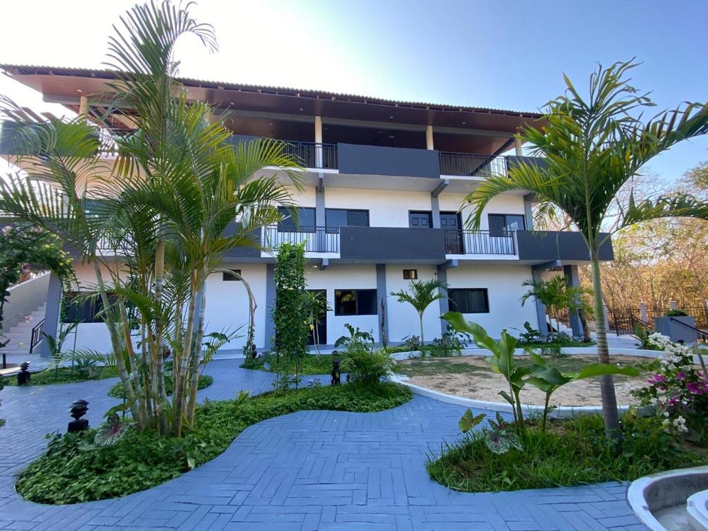 a resort with palm trees in front of a building at "Hotel Relax" in Las Pozas