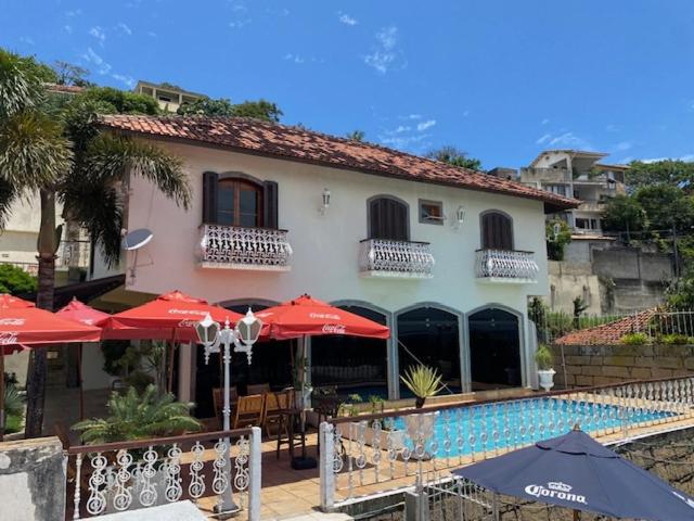 a building with umbrellas and a swimming pool in front of it at Restau de Marambaia in Barra de Guaratiba