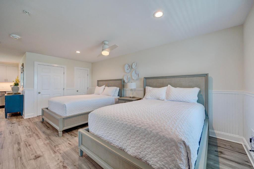 a bedroom with two beds with white sheets and wood floors at 3003 Queen Suite, 3rd Floor Cove in Surf City