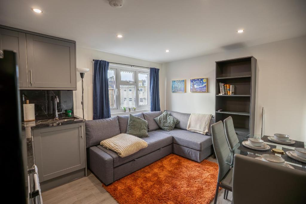 a living room with a gray couch and a kitchen at Cozy 2 Bed Flat in Town Centre in Royal Tunbridge Wells