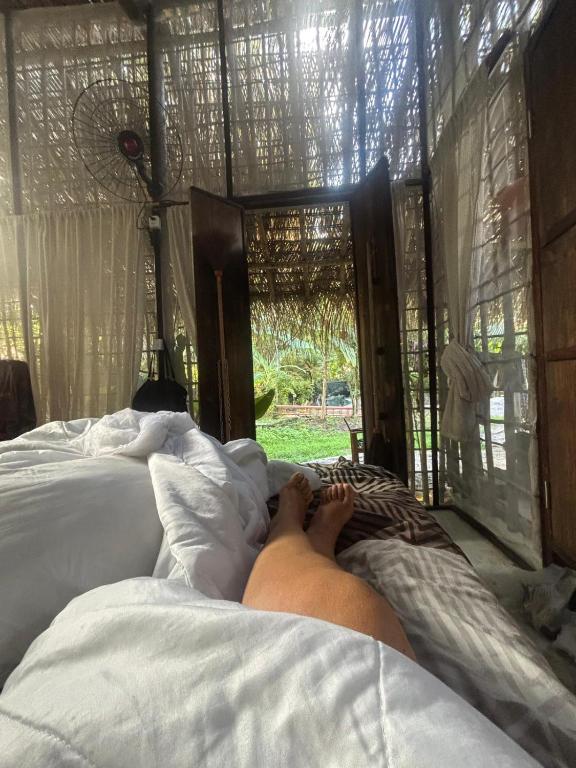 a person laying on a bed in a bedroom at REFUGIO do SAGRADO MORERE Tropical Lodge - A CASA das BRUXAS in Moreré