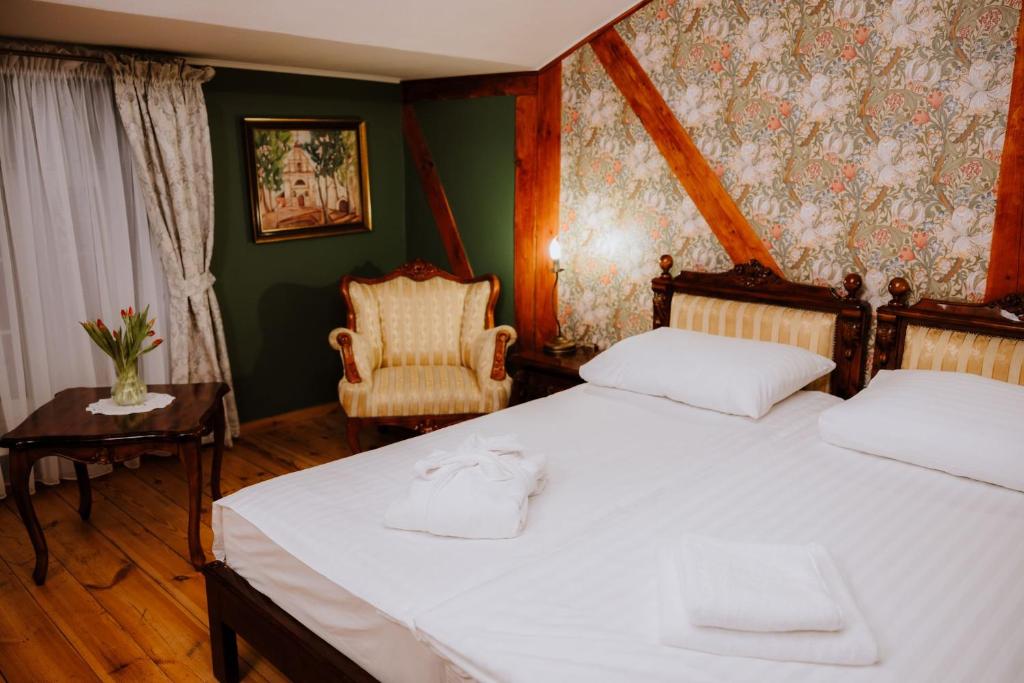 Cozy bedroom with twin beds, floral wallpaper, folded robe on bed, vintage armchair and tulips.