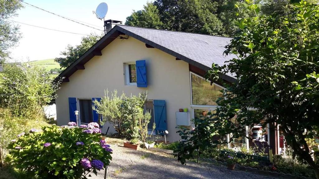 a small white house with blue shutters and flowers at Oxygène in Lasseube