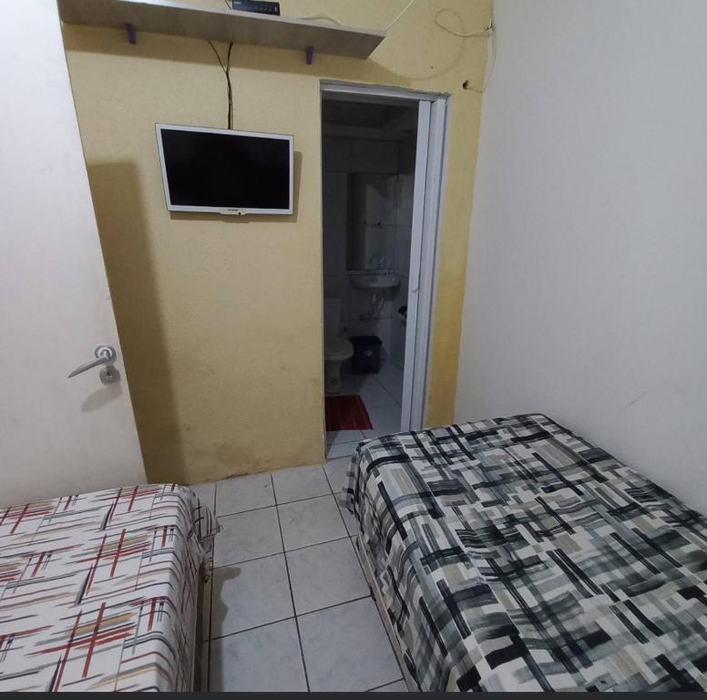 a bedroom with a bed and a tv on the wall at Hospedagem Setúbal in Recife