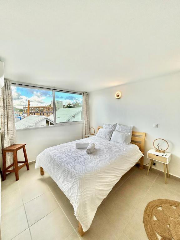 a bedroom with a bed and a large window at Vue mer sur la Marina, Le Juliana in Pointe-à-Pitre