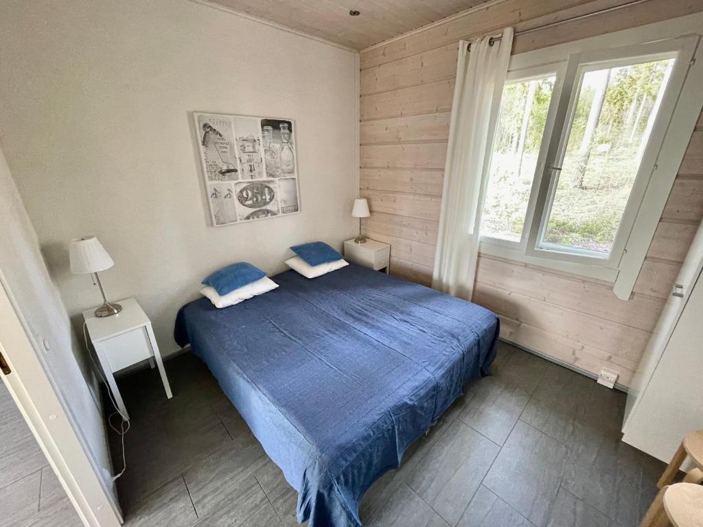 a bedroom with a blue bed and a window at Lakeside Cottages in Rastinniemi