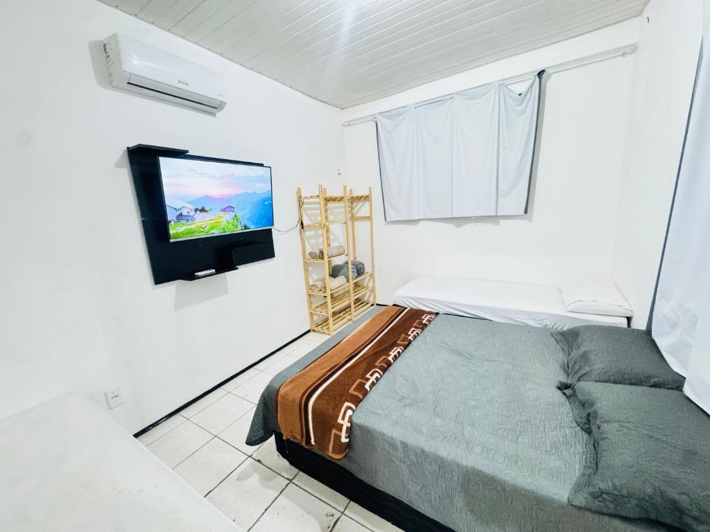 a bedroom with a bed and a flat screen tv at ap 2 quartos com ar e garagem bairro derby in Sobral