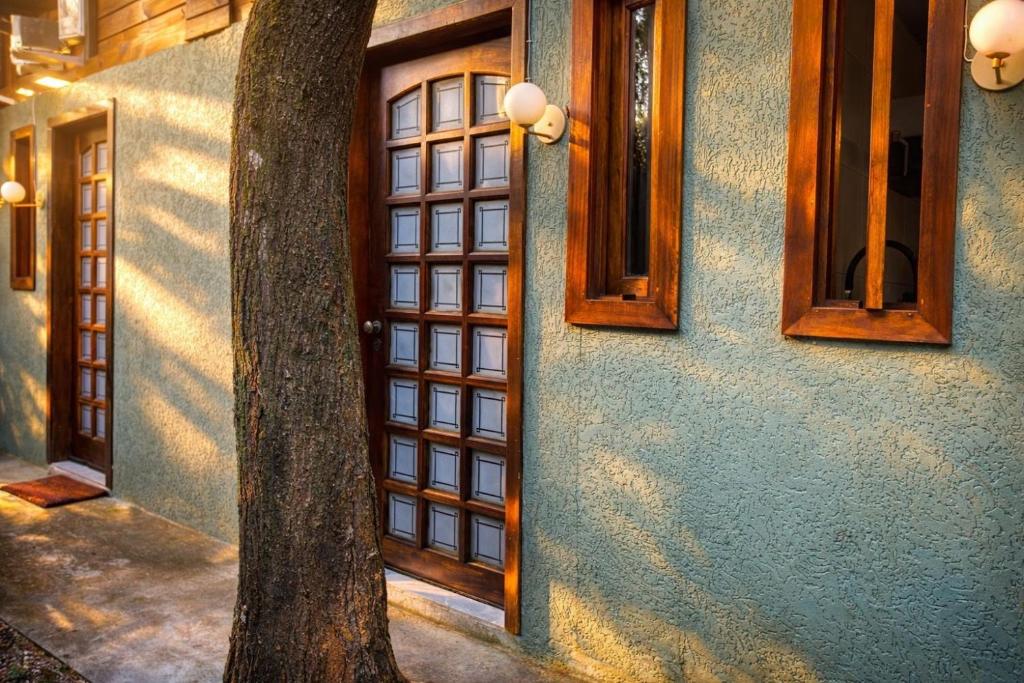 a door to a house with a tree next to it at Vilarejo hospedagem- Espaço Beco Carioca in Ilha do Mel