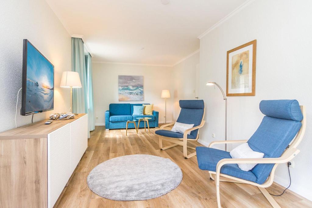 a living room with blue chairs and a tv at Ferienhaus Ankerplatz in Timmendorfer Strand