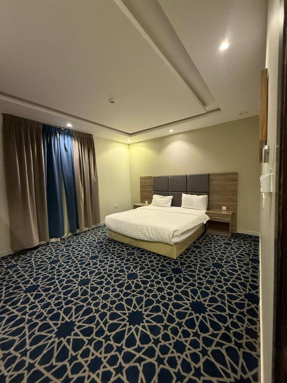a bedroom with a bed with a blue and white carpet at شاليهات وشقق ليالي رهيف in Abha