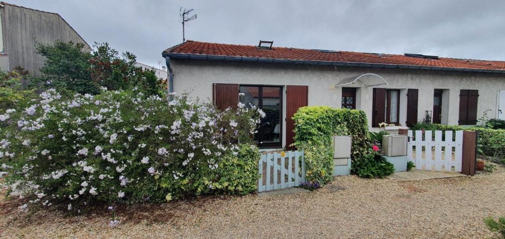 a small white house with a white fence and flowers at maisonnette bord de mer in Royan