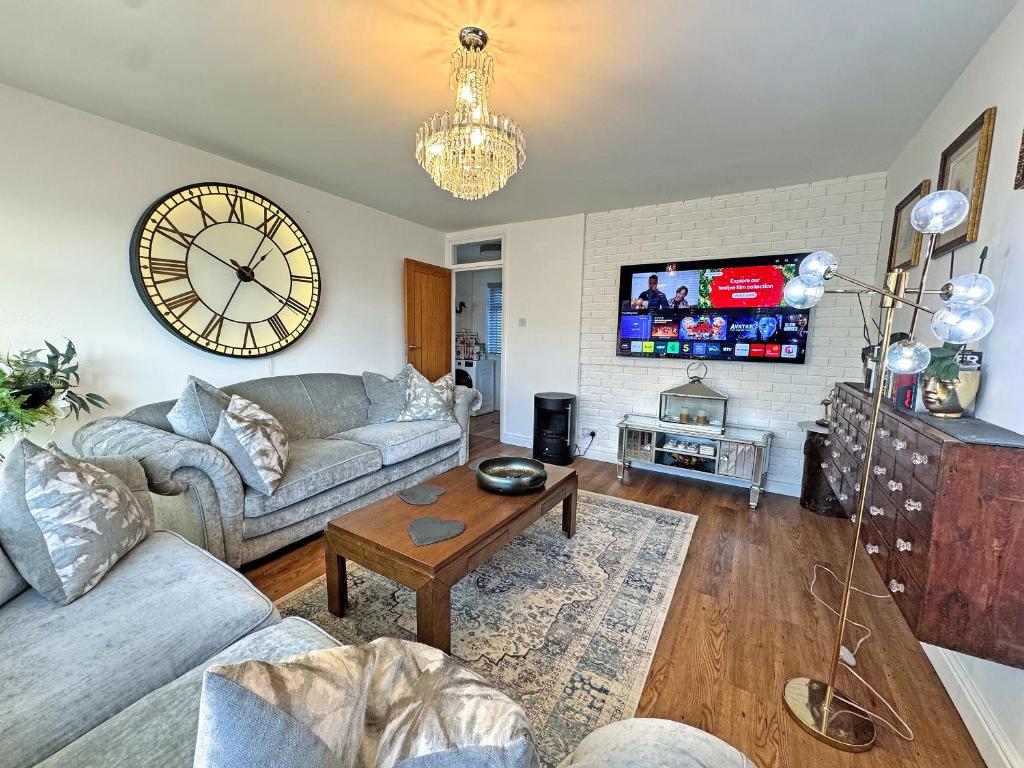 a living room with a couch and a clock on the wall at The Annexe in Peacehaven