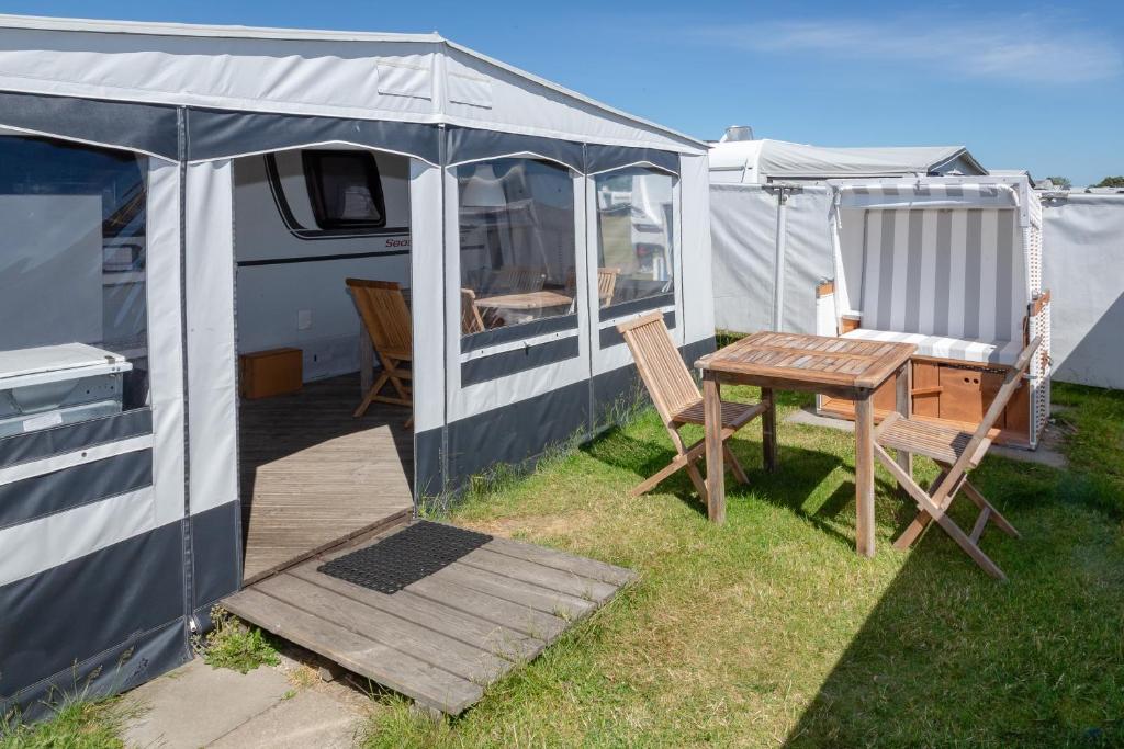 a tent and a table and chairs in a yard at Wohnwagenvermietung Sylt in Rantum