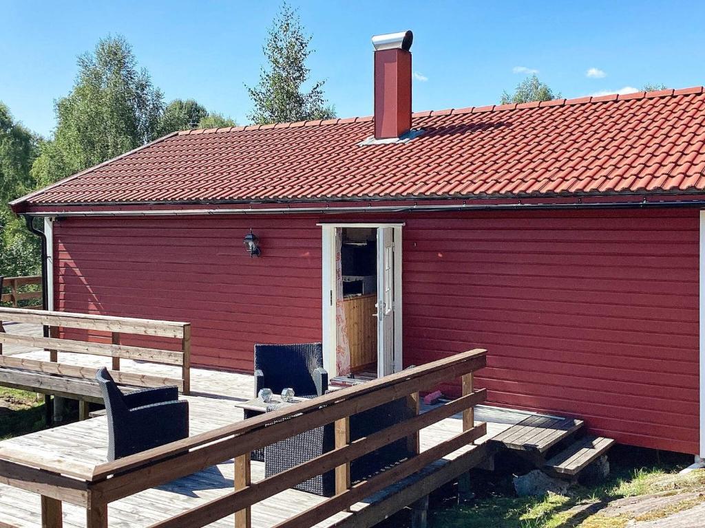 a red building with two chairs on a wooden deck at 4 person holiday home in BENGTSFORS in Bengtsfors