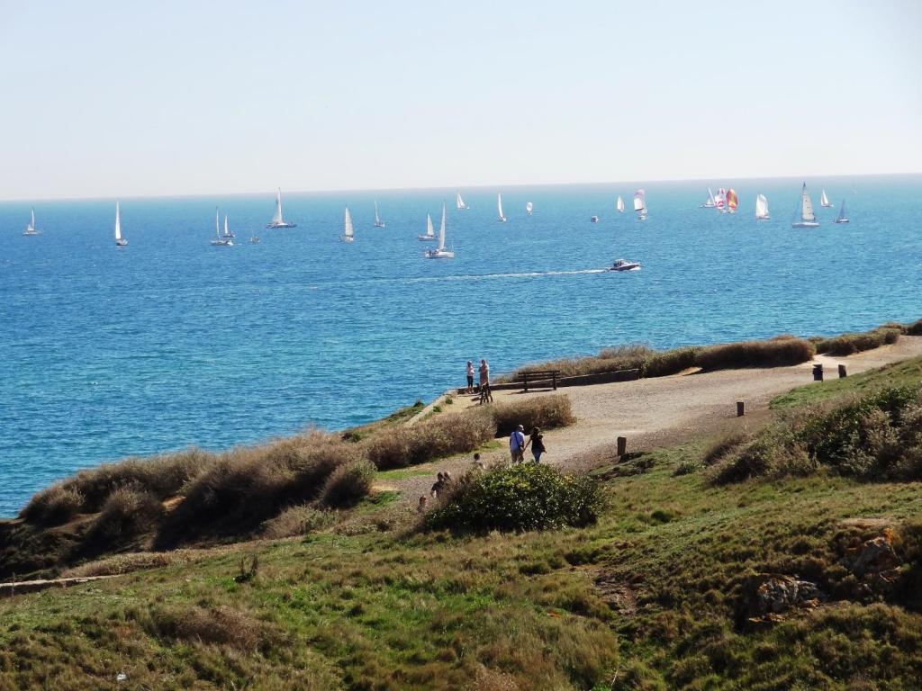 des personnes marchant sur une plage avec des bateaux dans l'eau dans l'établissement Hôtel Bellevue Cap d'Agde, au Cap d'Agde