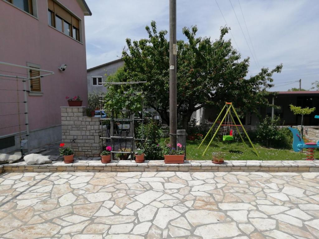 a stone patio with a garden with a swing at Apartmani Vesna in Kaštel