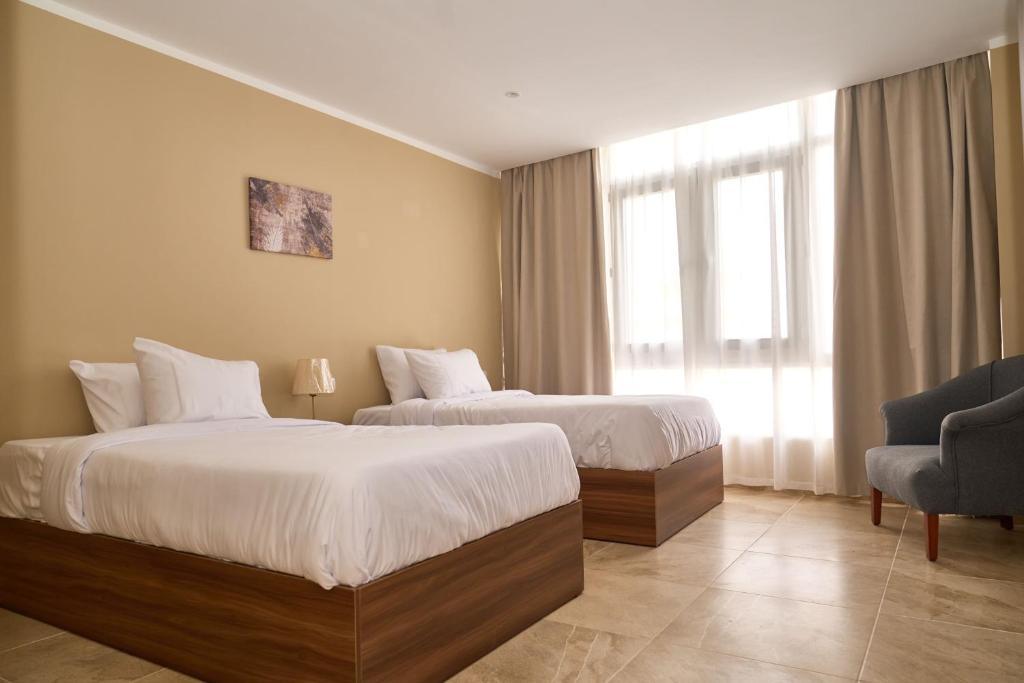 a hotel room with two beds and a chair at The Fit Stop Hostel in Hurghada