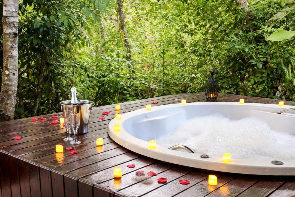 a bath tub sitting on a wooden table with candles at Chalés Pura Vida in Itacaré
