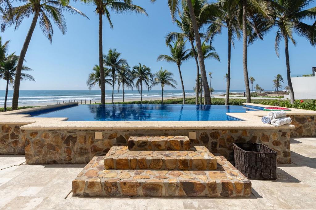a swimming pool with palm trees and the beach at Exclusive Oceanfront Apartment Beach access in Acapulco