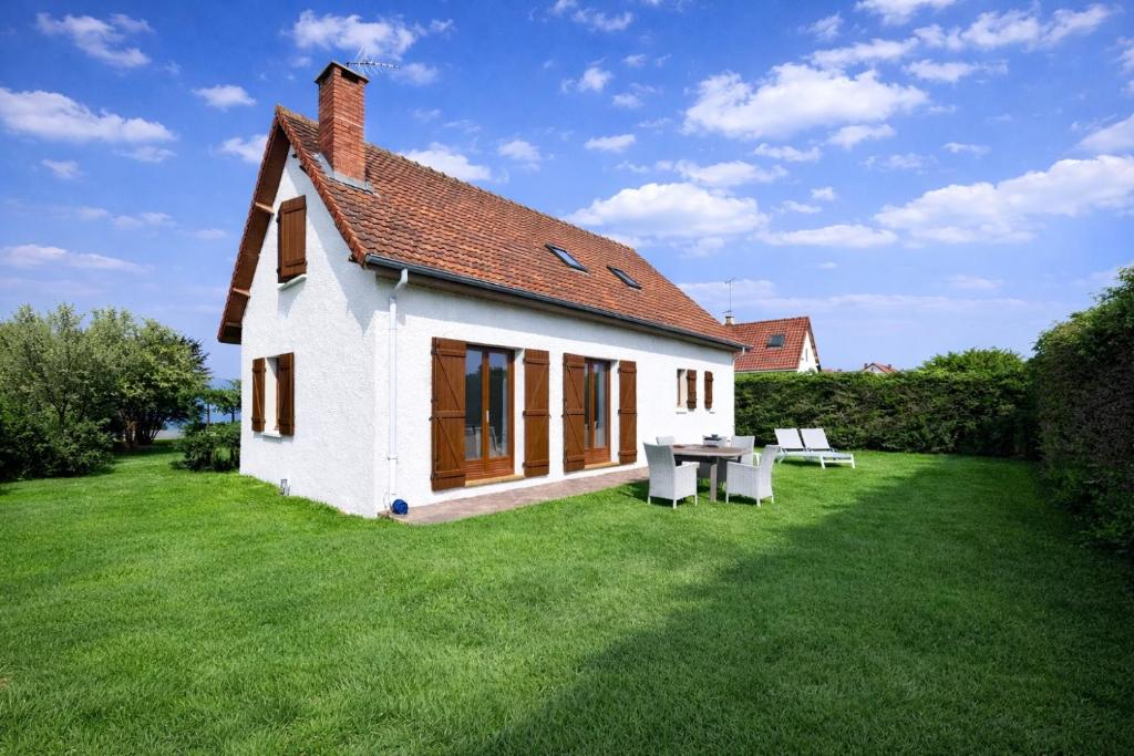a small white house with a table and two benches at Maison individuelle, 100m2, 3 chambres, jardin clos in Fort-Mahon-Plage