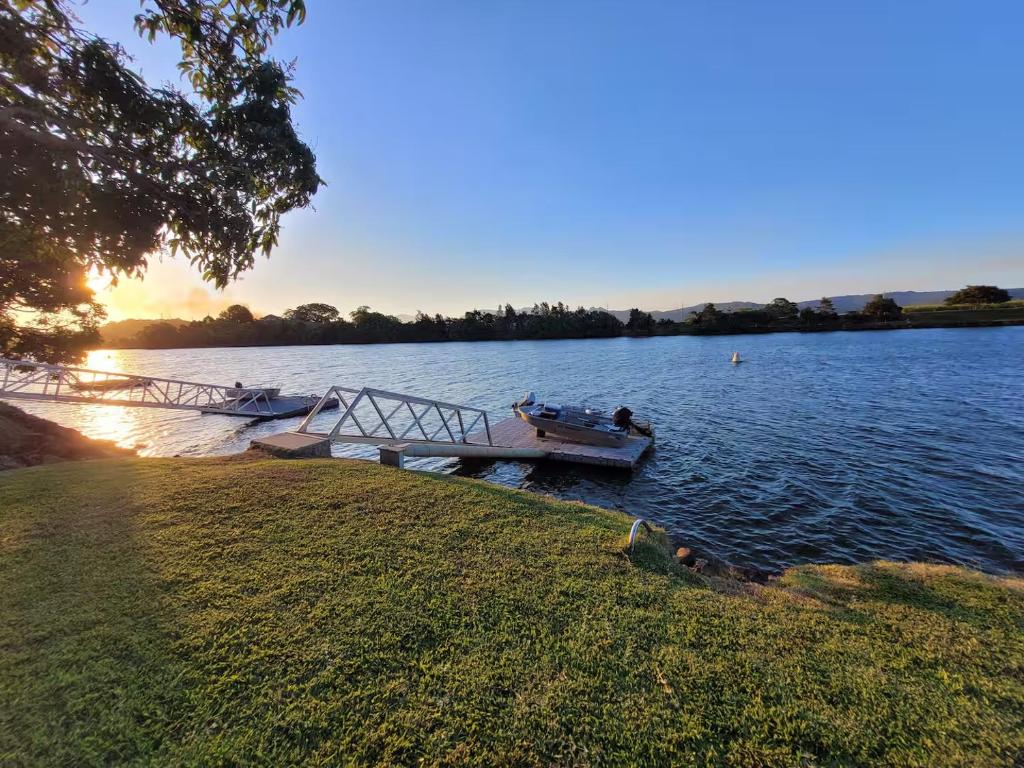 a boat is docked on a lake with a dock at Tweed River Waterfront Cottage in Murwillumbah