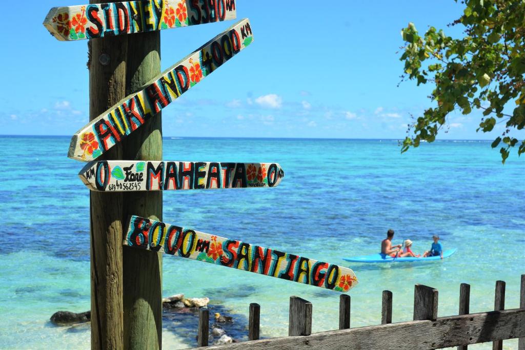 a pole with signs on it next to the ocean at Fare Maheata in Pihaena