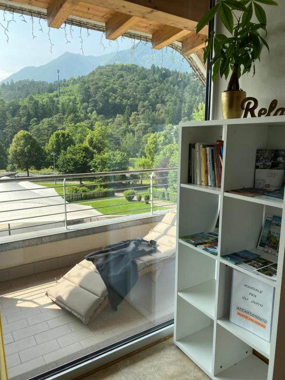 a book shelf in front of a window with a view at APPARTAMENTO MONTE - VALANDRO- in Comano Terme