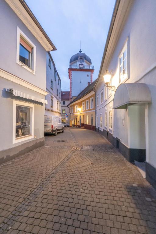 an empty street with a clock tower in the background at COY Apartments Leoben - Central near Uni & Station with 24 7 Check-in in Leoben